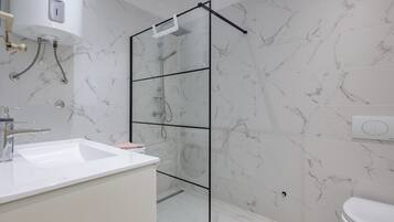 Ein modernes Badezimmer mit Duschkabine aus Glas, einem weißen Waschbecken und einer Toilette.