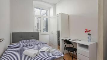 Ein Schlafzimmer mit Bett, Schreibtisch, Stuhl und Kleiderschrank.