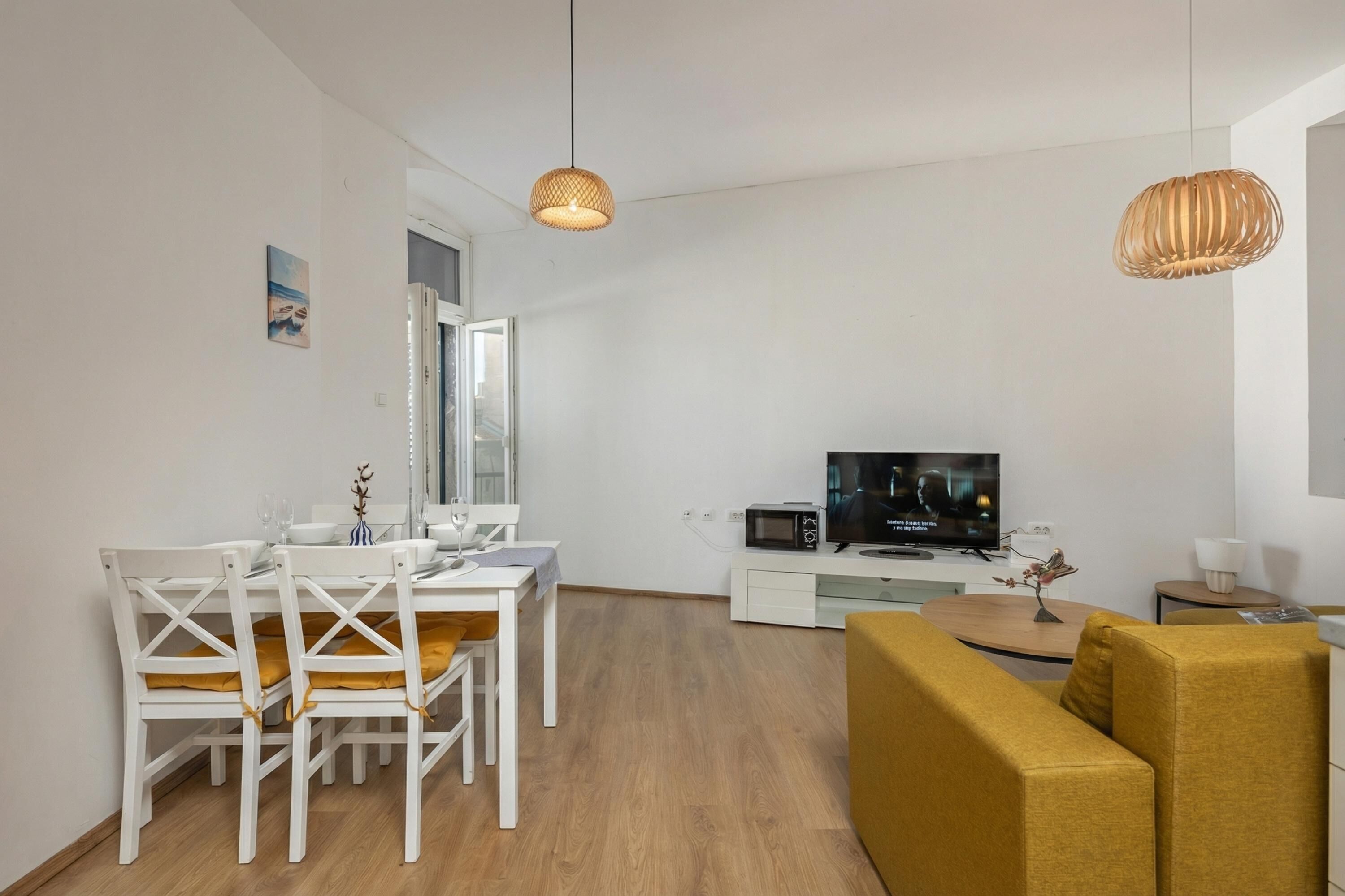 Una sala de estar moderna con comedor, un sofá, un televisor y un microondas.
