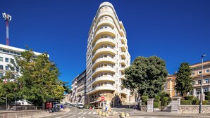 A modern multi-story building with a curved facade, located at a city intersection with a clear blue sky. - Anna | 4-Bedroom City Apartment (Rijeka)