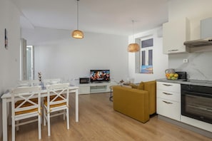 A modern kitchen with a microwave, oven, and a dining area with a white table and chairs.