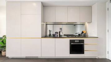 A modern kitchen with white cabinetry, a black oven, and a countertop with a sink and stove.