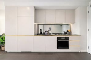 Una cucina moderna con mobili bianchi, un forno nero e un piano di lavoro con lavello e fornelli.