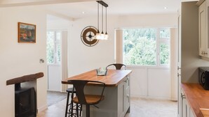 A modern kitchen with a wooden island, bar stools, a hanging light fixture, and a view of greenery outside. - 3 bedroom accommodation in Cinderford (Cinderford)
