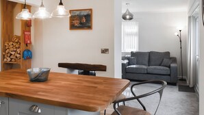 A modern kitchen with a wooden countertop, hanging pendant lights, and a fire extinguisher on the wall. - 3 bedroom accommodation in Cinderford (Cinderford)