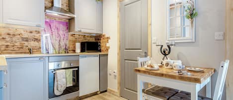 Une cuisine avec des meubles de rangement en bois, un four à micro-ondes, un four traditionnel et une table à manger avec des chaises.