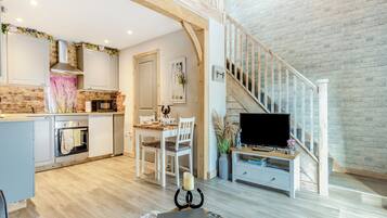 A spacious living area with a kitchen, dining table, and a staircase leading to an upper level.