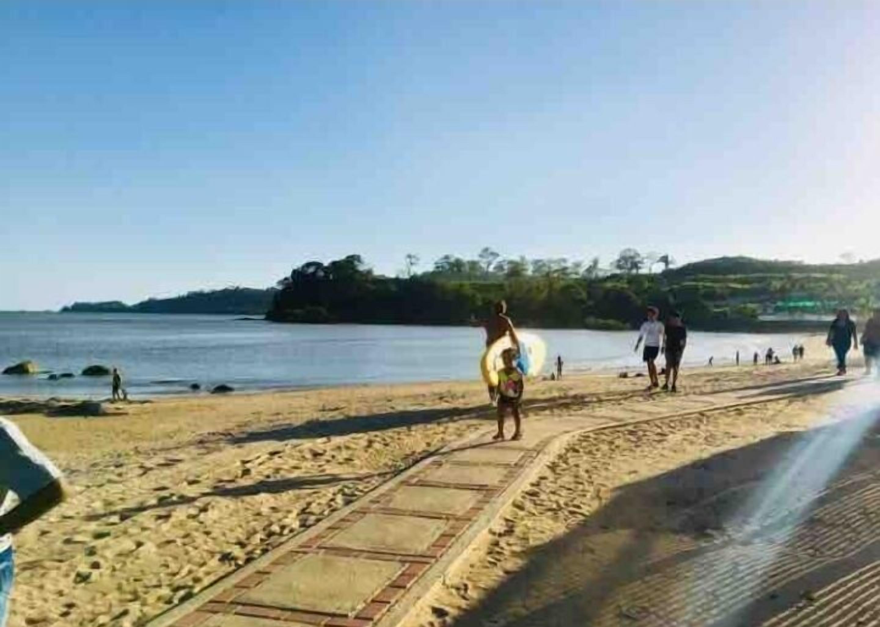 A sandy beach with a paved walkway.