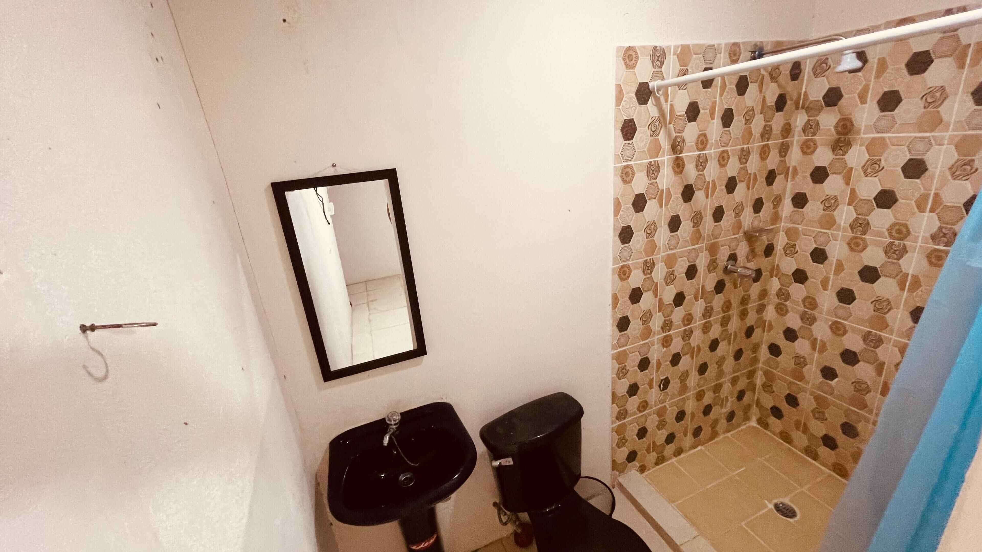 Un baño pequeño con inodoro, lavamanos y ducha.