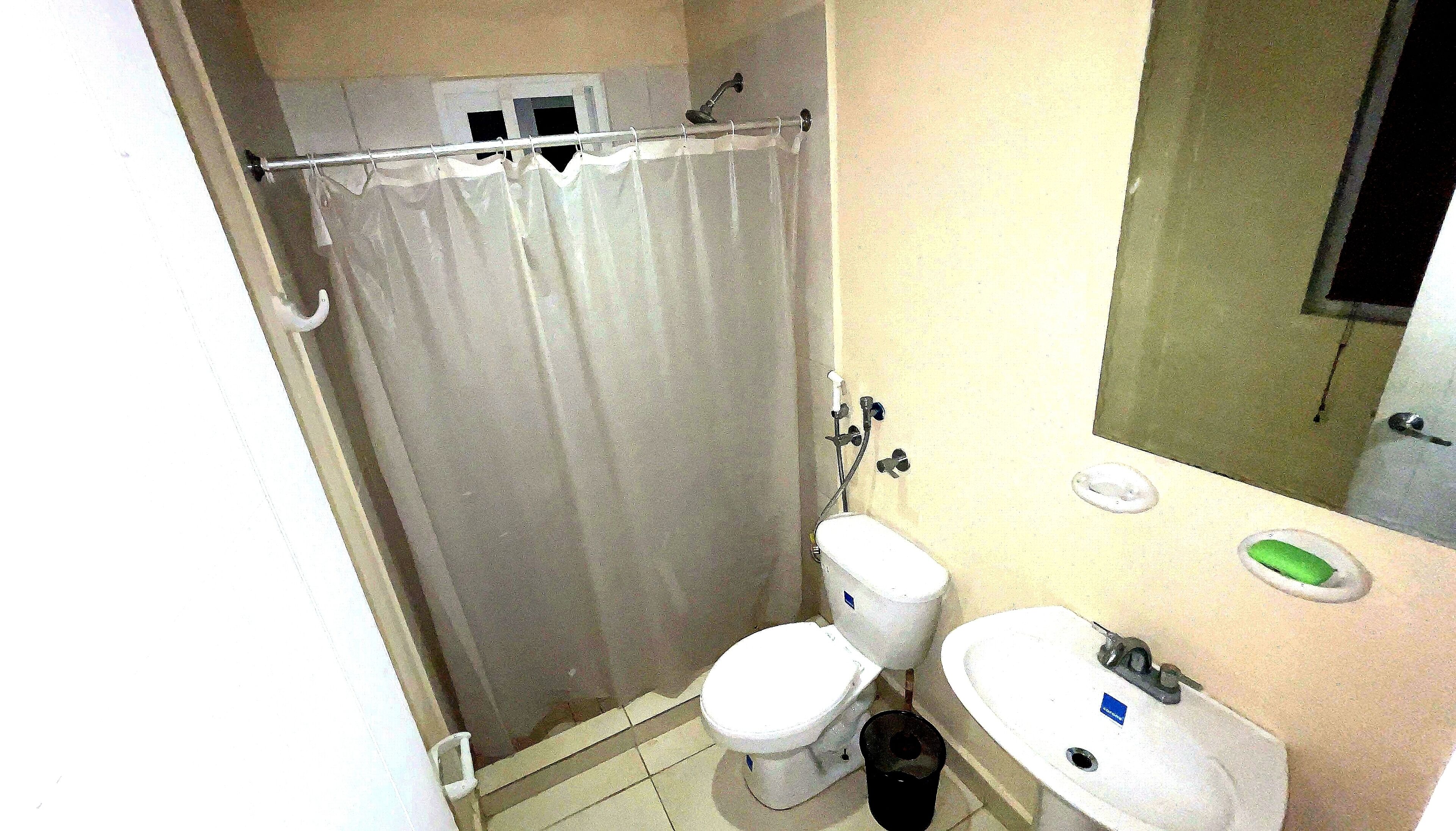 A small bathroom with a shower curtain, toilet, sink, and mirror.