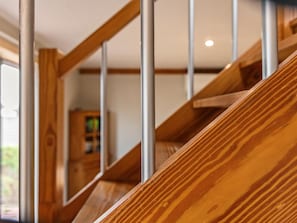 A wooden staircase with metal railings, leading to a room with a wooden cabinet and a window.