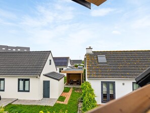 Un quartier résidentiel où les maisons sont dotées de toits inclinés, certaines étant équipées de panneaux solaires, et où l’on trouve de petits jardins.