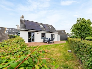 A house with solar panels, a patio with chairs, and a garden.