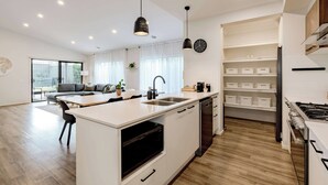 Una cuina moderna amb una illa central, electrodomèstics integrats i una zona de menjador amb sofà.