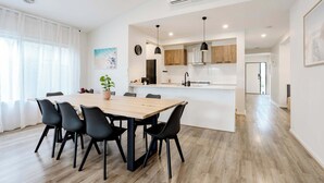 A modern kitchen with a central island, wooden flooring, and pendant lighting. - Coastal Family Retreat - Relaxed Living with Spa (Torquay)