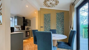 A modern kitchen with grey cabinets, a black range hood, and a wooden floor. - 1 bedroom accommodation in Millom (Millom)