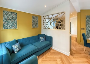 A modern living room with a blue sofa, decorative wall panels, and a geometric wall design.