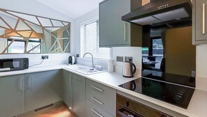 A modern kitchen with a microwave, kettle, and stove. - 1 bedroom accommodation in Millom (Millom)