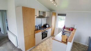 A modern kitchen with a herringbone floor, a gas stove, a built-in oven, and a window with a view. - 1 bedroom accommodation in Llanon (Llanon)
