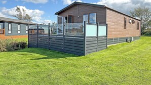 A modern mobile home with a large deck, a window, and a brick exterior. - 1 bedroom accommodation in Llanon (Llanon)