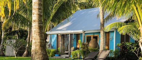 Una casa con fachada azul, un porche cubierto y un césped con una silla de descanso.