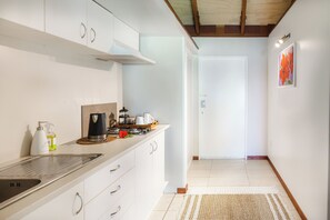 Een moderne keuken met witte kastjes, een RVS-spoelbak en een koffiezetapparaat.