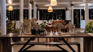 A dining area with a long table set for two, featuring clear glassware and a small plant centerpiece. - Oarsman's Bay Lodge - Adults Only (Nacula Island)