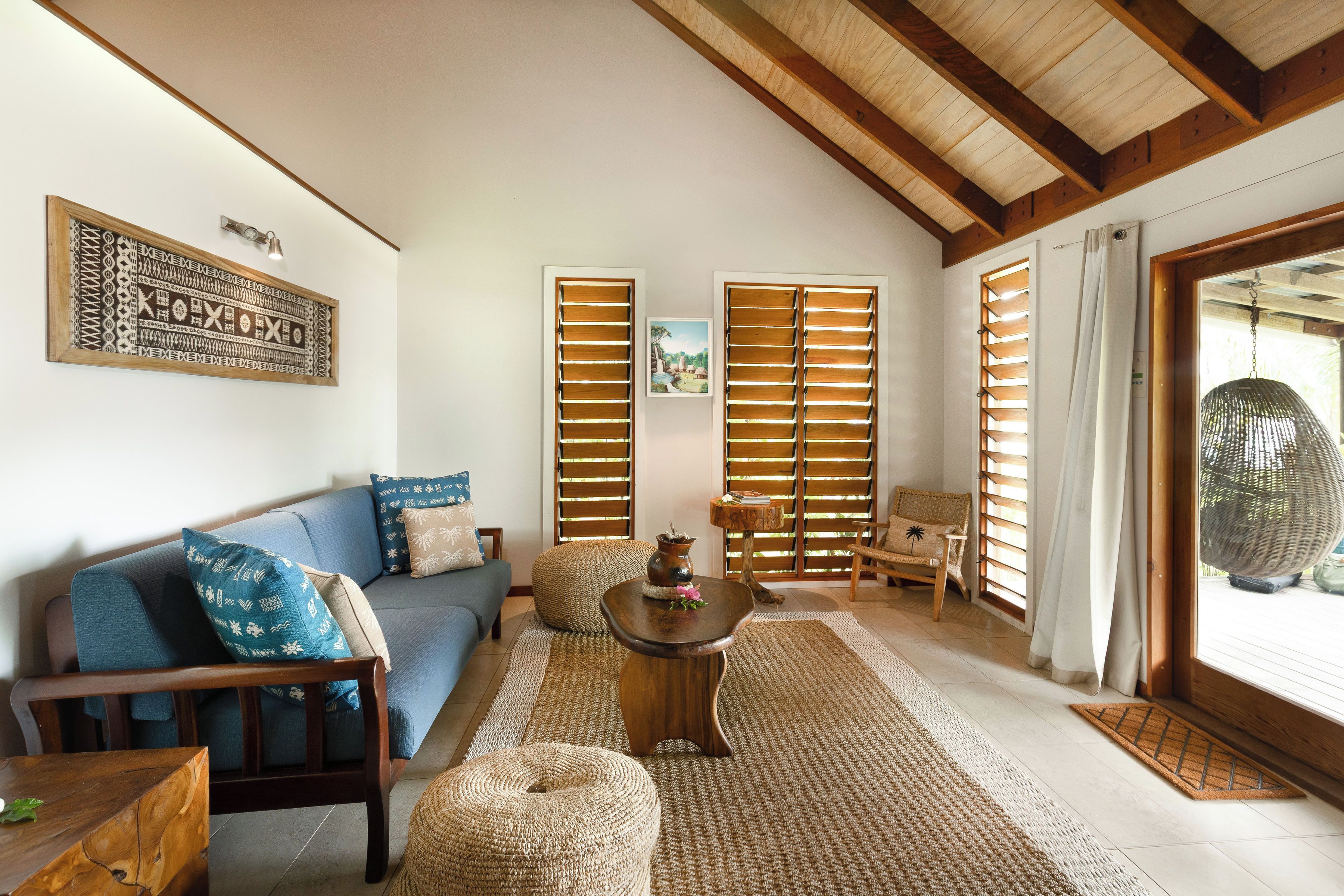 A living room with a sofa, coffee table, and wicker furniture.