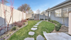 A modern house with a well-maintained lawn, stone pathway, and a variety of shrubs and plants. - Woodward Links • Walk to CBD • Near Duntryleague (Orange)