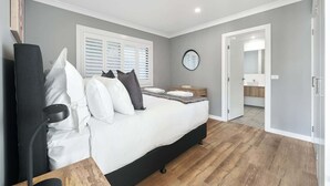 A bedroom with a bed, bedside table, and a view of the bathroom. - Woodward Links • Walk to CBD • Near Duntryleague (Orange)