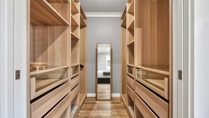 A narrow walk-through closet with wooden shelving and drawers, leading to a mirrored closet door. - Woodward Links • Walk to CBD • Near Duntryleague (Orange)