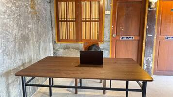 A wooden table with a laptop, a concrete wall, and wooden doors with a sign.
