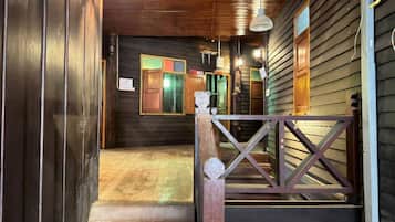 A wooden staircase leading to a room with a wooden floor, a wooden railing, and a view of the outside.