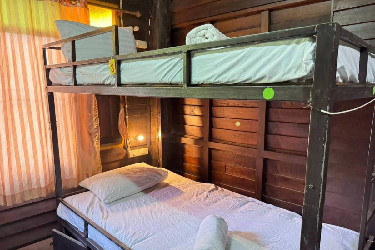 A bunk bed room with a wooden interior, a curtain, and a wall-mounted light.