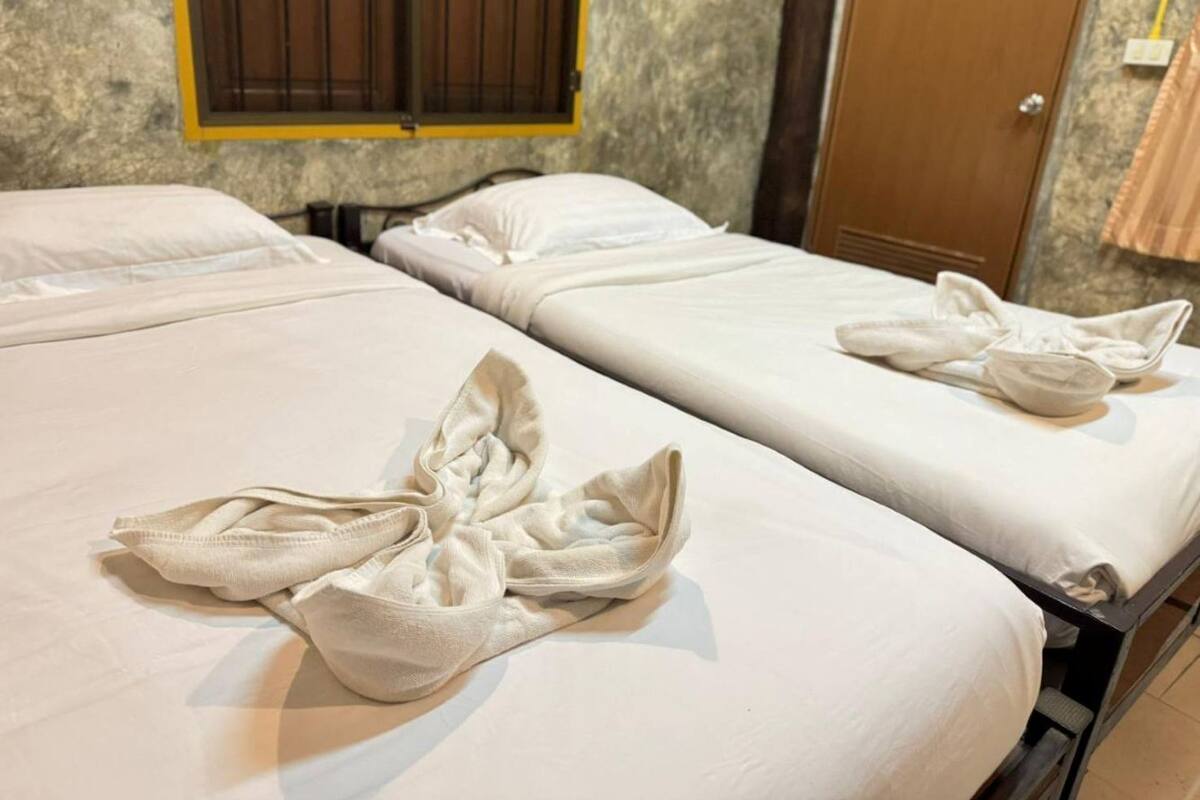 A hotel room with two beds, each with neatly folded towels.