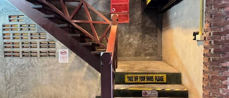 Una escalera con barandilla de metal, señales de precaución y un letrero que dice 'NO DRUGS'.