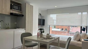 A modern apartment with a kitchenette, a dining area, and a living space with a large window. - NOK Modern Apartment in Chapinero (Bogotá)