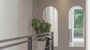 Un intérieur moderne avec un escalier, une plante en pot et une vue à travers une porte en arc de cercle.