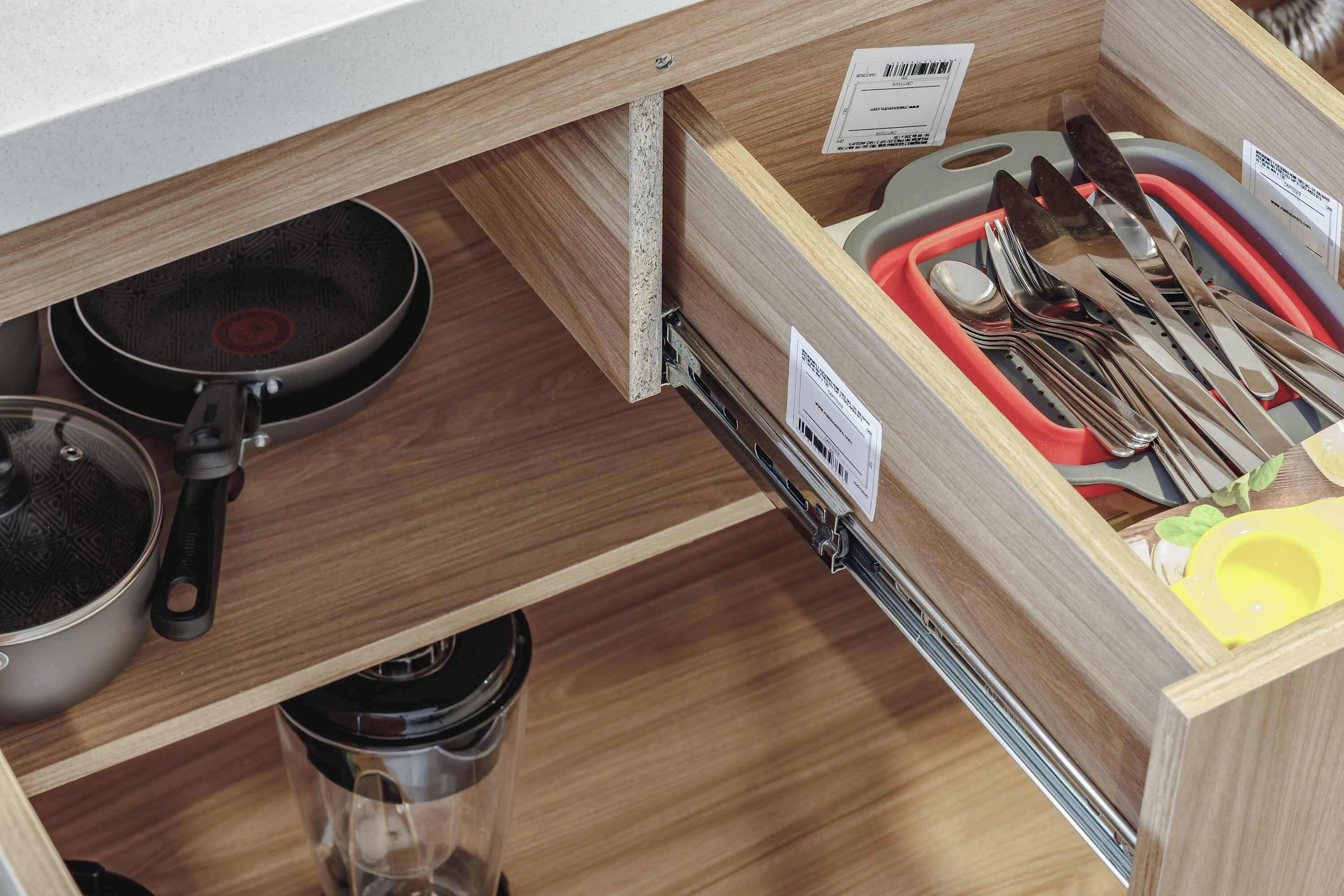 Eine Küchenschublade mit Geschirr, einer Pfanne und einer Kaffeemaschine.