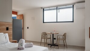 Ein Hotelzimmer mit einem Bett, einem kleinen Tisch mit zwei Stühlen, einem Fenster und einer Tür.