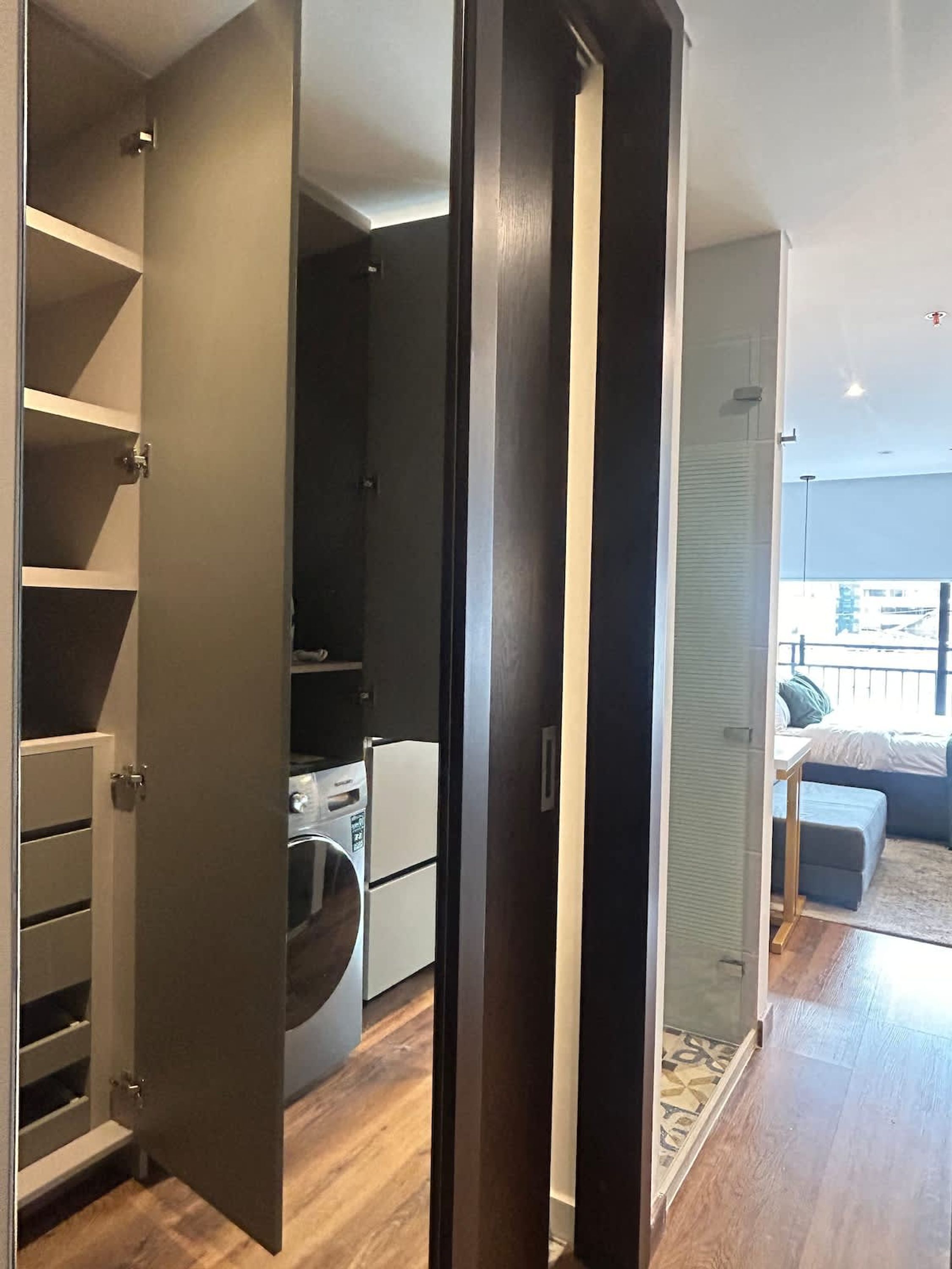 A modern apartment with a kitchen, a laundry area, and a living room with a sofa and a coffee table.