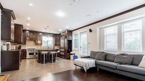 A modern kitchen with dark wood cabinets, a central island with bar stools, and a built-in oven.