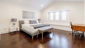 A bedroom with a bed, bedside tables, a desk, and a window.