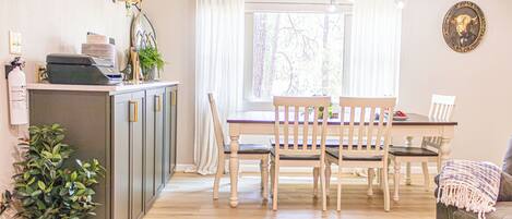 A dining area with a wooden table and chairs, a potted plant, and a chandelier.
