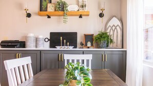 A dining area with a wooden table, chairs, a potted plant, and kitchen items on the counter. - Royal Heaven (Ruidoso)
