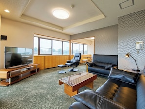 A modern living room with a flat-screen TV, leather sofa, and a wooden coffee table.