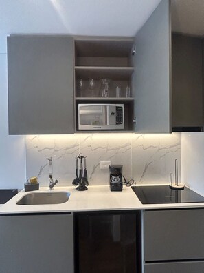 A modern kitchen with a built-in microwave, a coffee maker, and a sink.