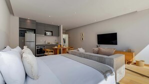 Ein modernes Hotelzimmer mit einem großen Bett, einer Couch, einem Essbereich und einem an der Wand befestigten Fernseher.