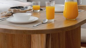 Ein Frühstückstisch mit einem Saftkrug, zwei Orangensäften, einer Schüssel und einem Teller.