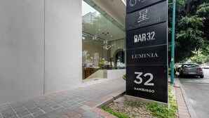 A modern building with a glass facade and a sign indicating 'BAR 32 LUMENIA 32 HAMBURG'. - Capitalia | Jacuzzi Upstairs, Car Downstairs (Ciudad de México)